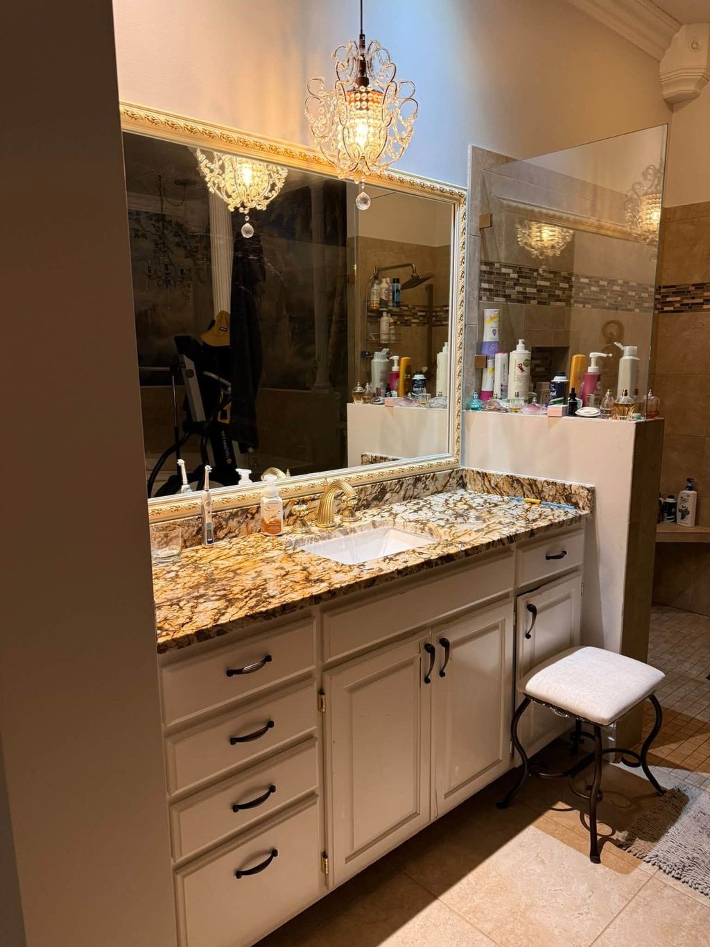 Bathroom vanity with granite counter, framed mirror and a crystal chandelier